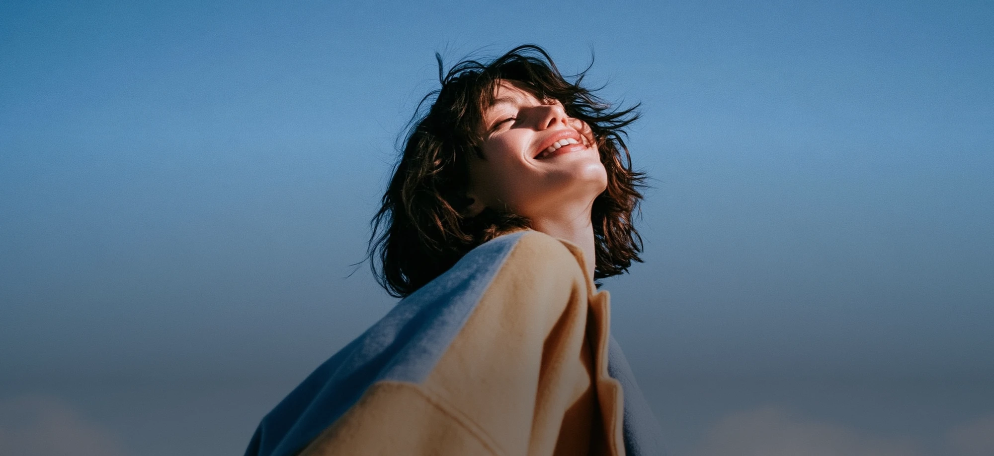 Person smiling up at a clear sky